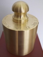 Weight of Skin, brass, oak. 40”x8”x8”. The brass weight corresponds to the weigh